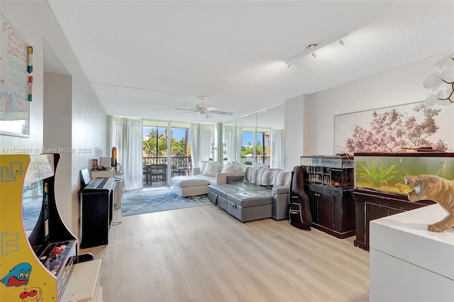 living area with expansive windows, ceiling fan, a textured ceiling, and light wood-style flooring