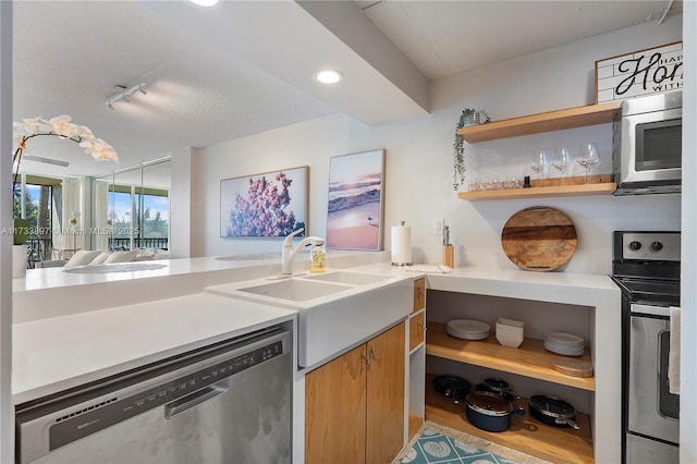 kitchen featuring appliances with stainless steel finishes, rail lighting, light countertops, open shelves, and a sink