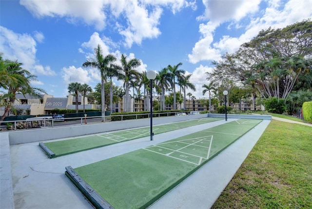 view of community with shuffleboard and a yard