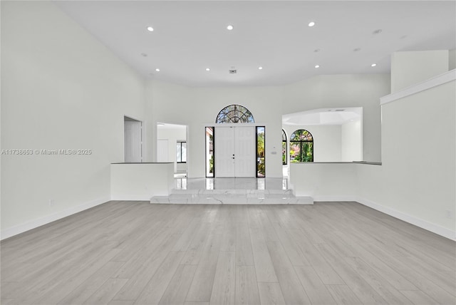 unfurnished living room featuring light hardwood / wood-style flooring and a high ceiling