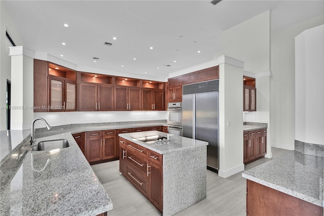 kitchen featuring appliances with stainless steel finishes, light stone countertops, sink, and a kitchen island