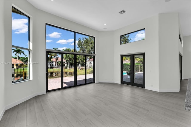 spare room with french doors, a high ceiling, and light wood-type flooring