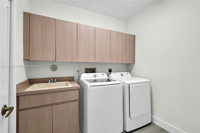 clothes washing area with sink, washer and clothes dryer, and cabinets