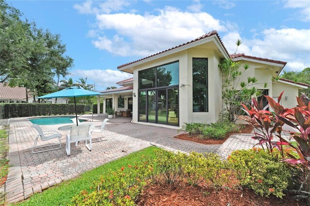 back of house with a fenced in pool and a patio area