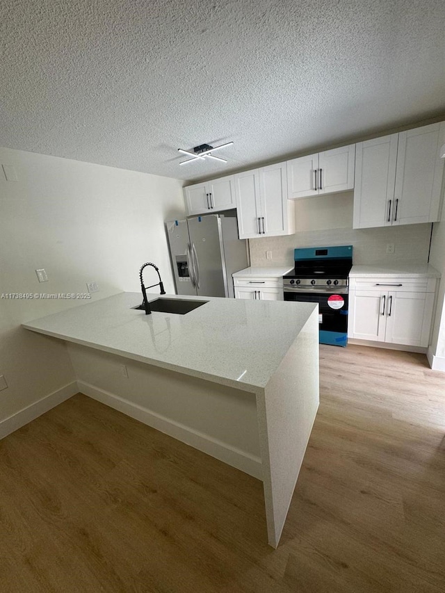 kitchen featuring sink, white cabinetry, stainless steel appliances, kitchen peninsula, and light wood-type flooring