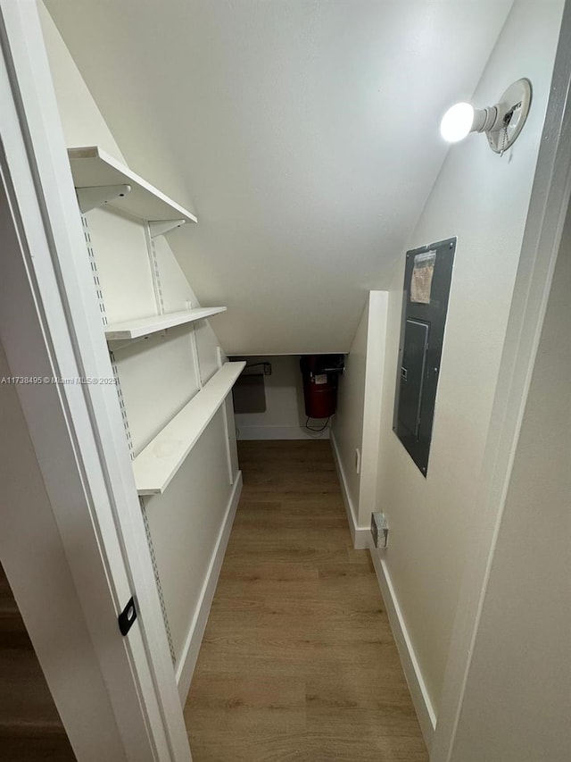 interior space with vaulted ceiling, electric panel, and light hardwood / wood-style floors