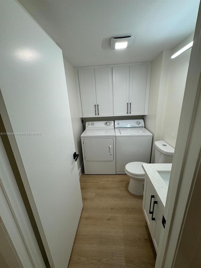 bathroom featuring wood-type flooring, toilet, and washer and clothes dryer