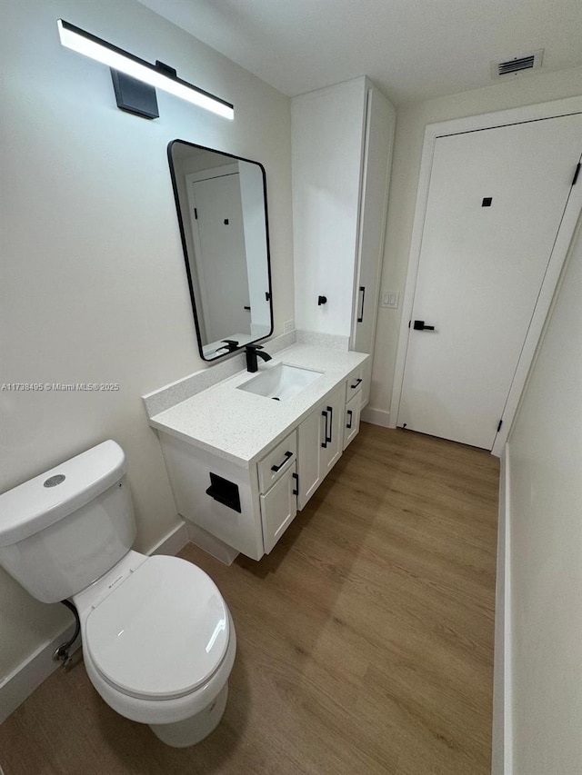 bathroom featuring hardwood / wood-style flooring, vanity, and toilet