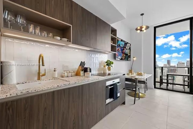 kitchen featuring oven, a wall of windows, hanging light fixtures, dark brown cabinetry, and black electric cooktop