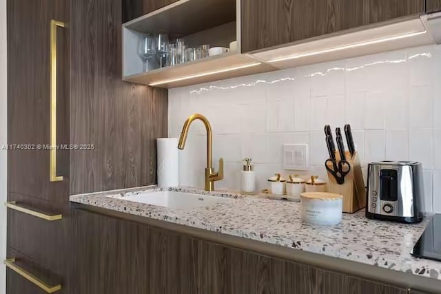 kitchen featuring light stone counters, sink, and tasteful backsplash