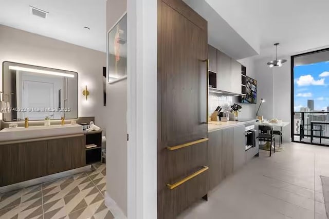 kitchen with pendant lighting, a chandelier, floor to ceiling windows, and stainless steel oven