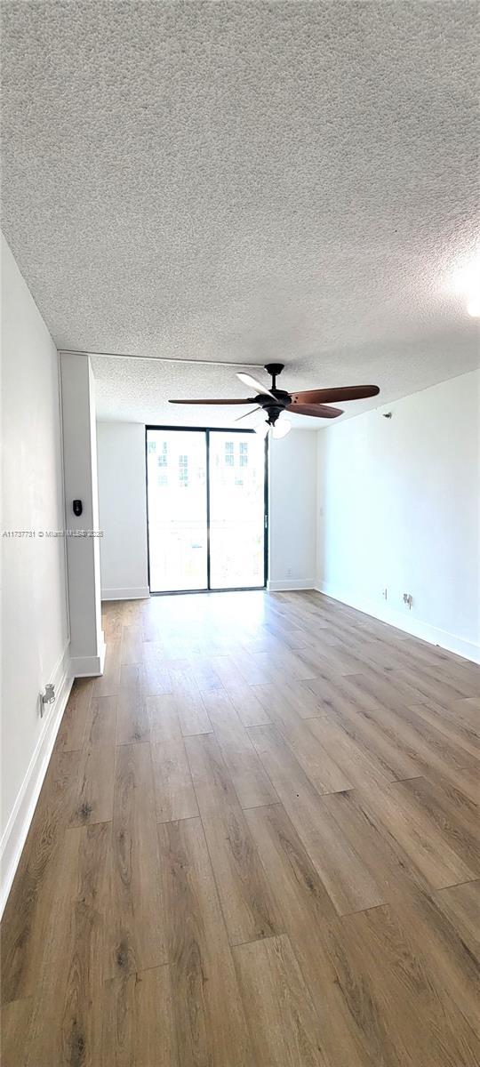 spare room with ceiling fan, wood-type flooring, and a textured ceiling