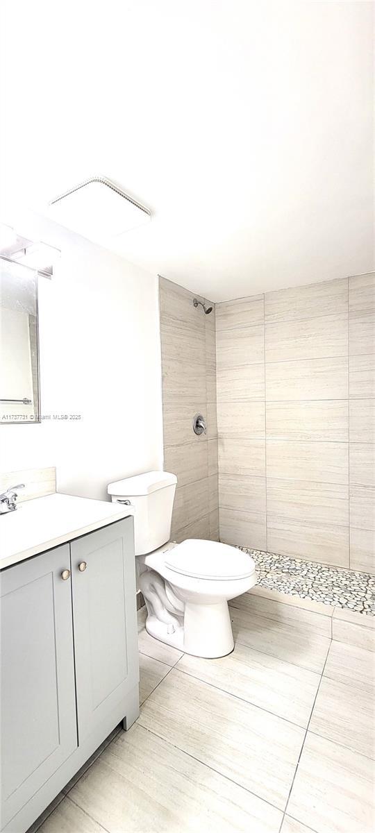 bathroom featuring vanity, toilet, and tiled shower