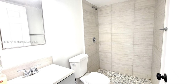 bathroom with tiled shower, vanity, and toilet