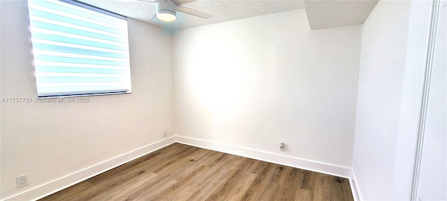 empty room with a textured ceiling, wood-type flooring, and ceiling fan