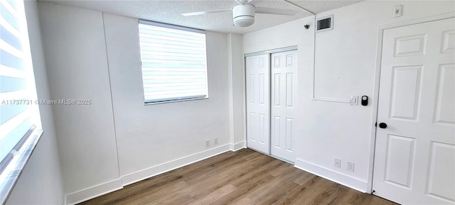 unfurnished bedroom with hardwood / wood-style flooring, a closet, ceiling fan, and a textured ceiling