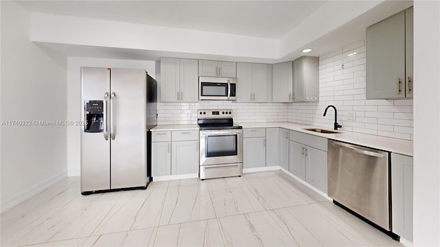 kitchen with stainless steel appliances, gray cabinets, sink, and backsplash