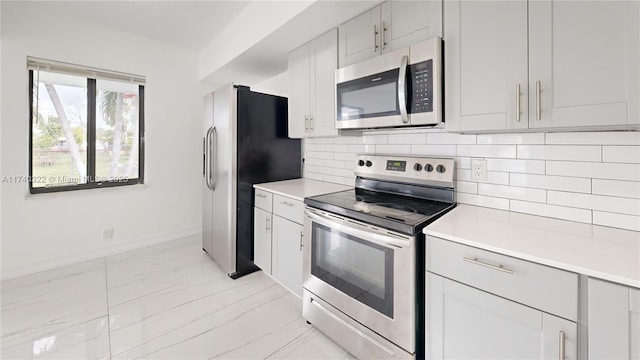 kitchen featuring stainless steel appliances, white cabinets, and decorative backsplash