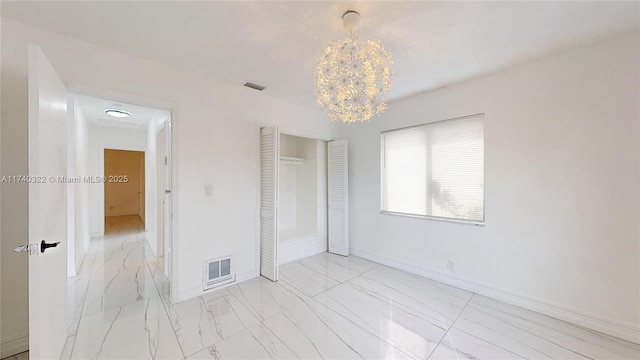 unfurnished bedroom with a notable chandelier and a closet