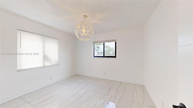 unfurnished room featuring an inviting chandelier