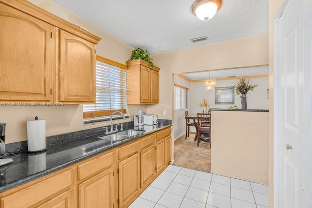 kitchen with pendant lighting, sink, dark stone counters, light tile patterned floors, and light brown cabinets