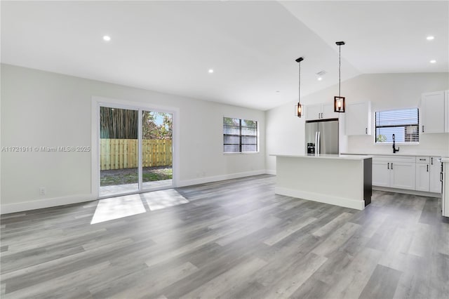 kitchen with stainless steel refrigerator with ice dispenser, white cabinetry, a kitchen island, and pendant lighting