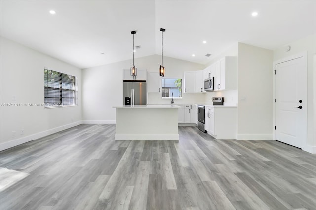 kitchen featuring appliances with stainless steel finishes, plenty of natural light, pendant lighting, a kitchen island, and white cabinets