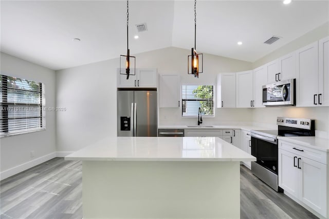 kitchen with pendant lighting, sink, appliances with stainless steel finishes, a center island, and white cabinets