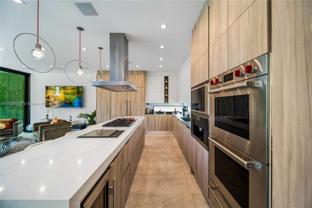 kitchen with pendant lighting, light tile patterned floors, appliances with stainless steel finishes, light stone countertops, and island exhaust hood