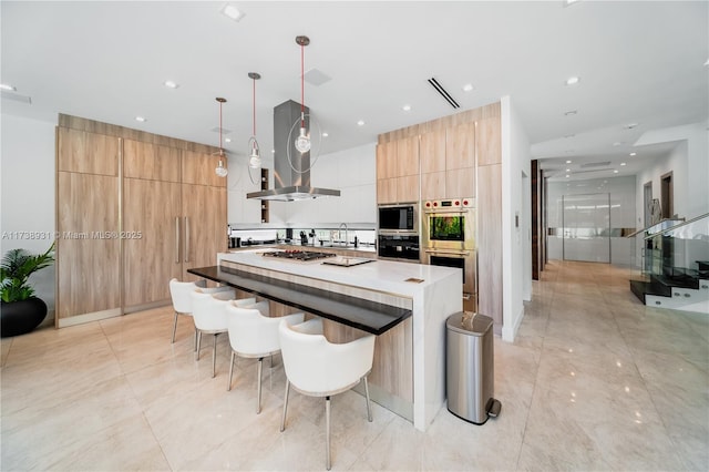 kitchen featuring a kitchen island, a kitchen bar, hanging light fixtures, island exhaust hood, and stainless steel appliances