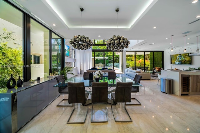 dining space with beverage cooler, a tray ceiling, a wall of windows, and a chandelier