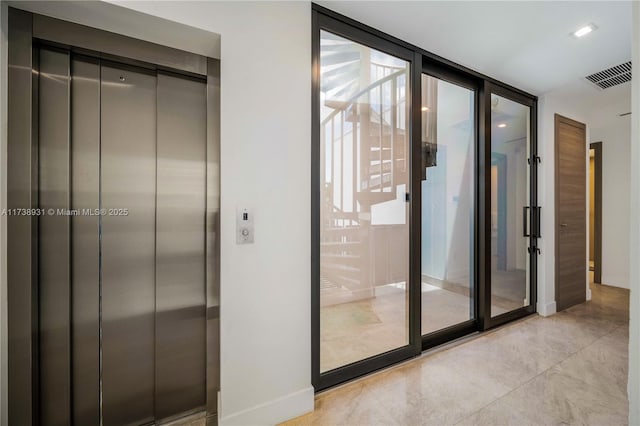 entryway with concrete flooring, visible vents, baseboards, floor to ceiling windows, and elevator