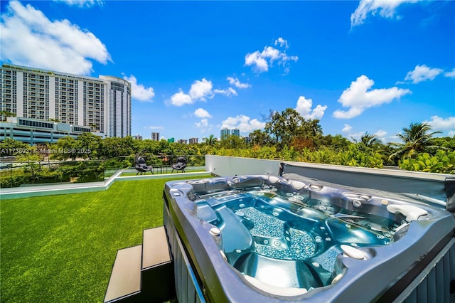 view of pool featuring a view of city, a yard, and a hot tub