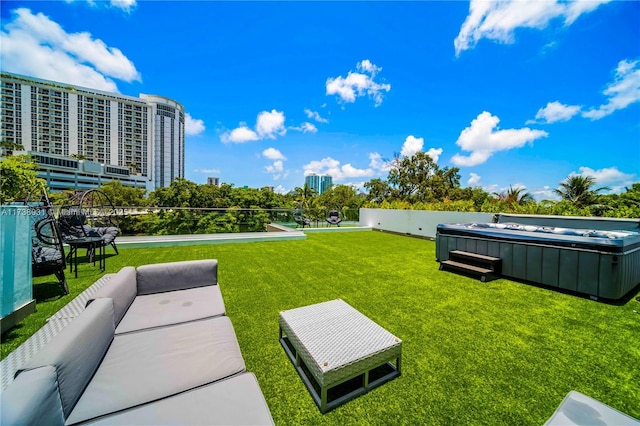 view of home's community with a city view, a lawn, an outdoor living space, and a hot tub