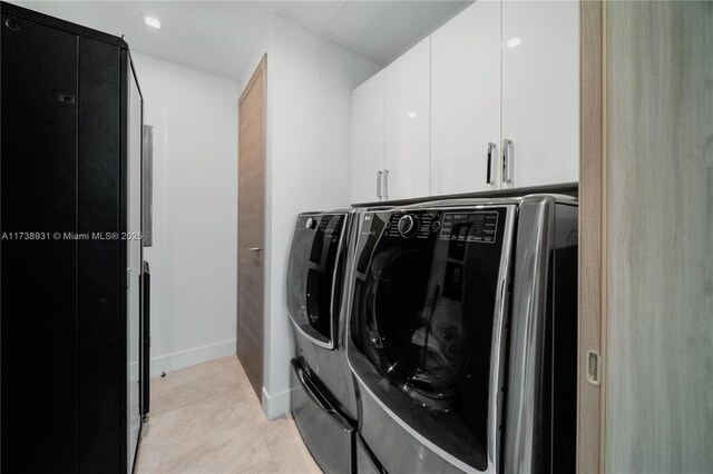 clothes washing area featuring cabinets and separate washer and dryer