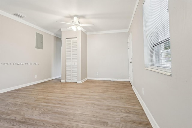 spare room featuring ceiling fan, ornamental molding, electric panel, and light hardwood / wood-style flooring