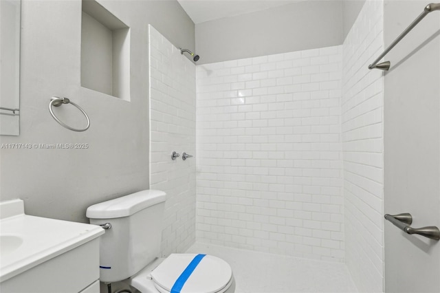 bathroom with vanity, toilet, and a tile shower