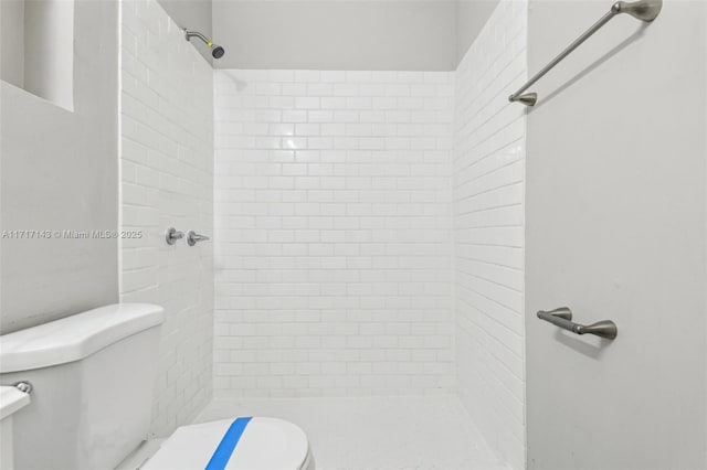 bathroom with tiled shower and toilet