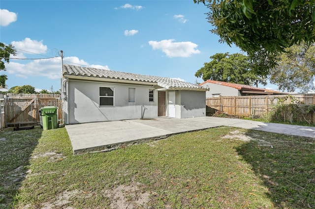 back of property with a patio area and a lawn