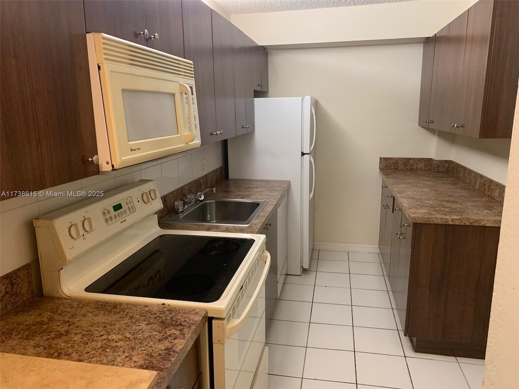 kitchen featuring sink, dark brown cabinets, light tile patterned floors, white appliances, and decorative backsplash