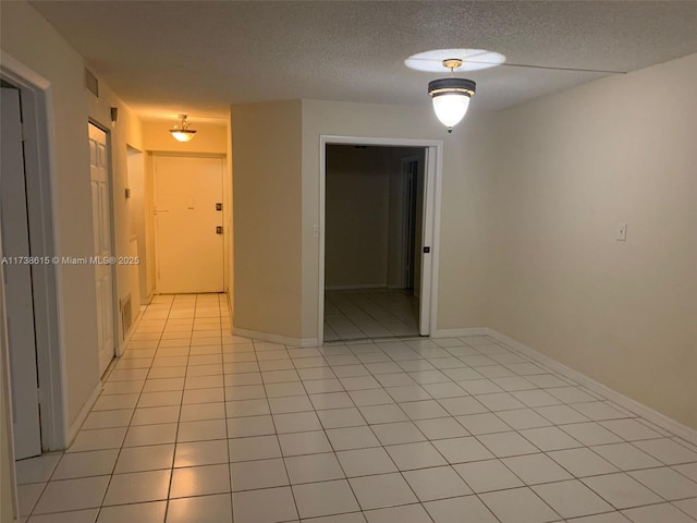 tiled empty room with a textured ceiling