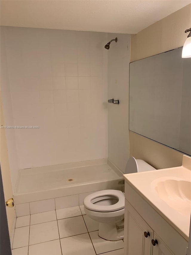 bathroom featuring vanity, tile patterned floors, toilet, and tiled shower