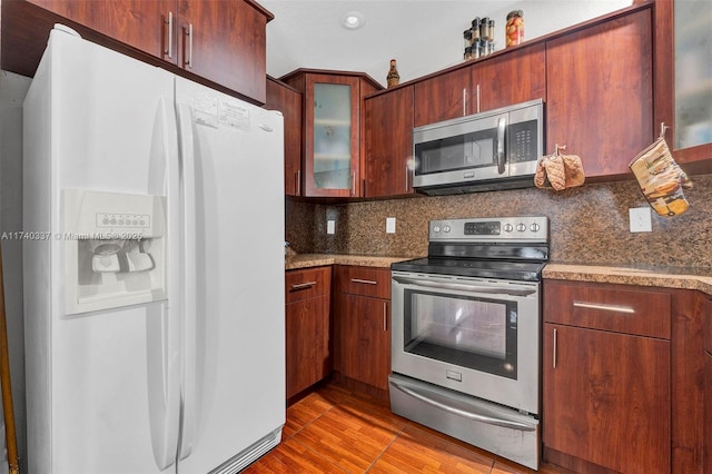 kitchen featuring light hardwood / wood-style floors, backsplash, stainless steel appliances, and dark stone counters