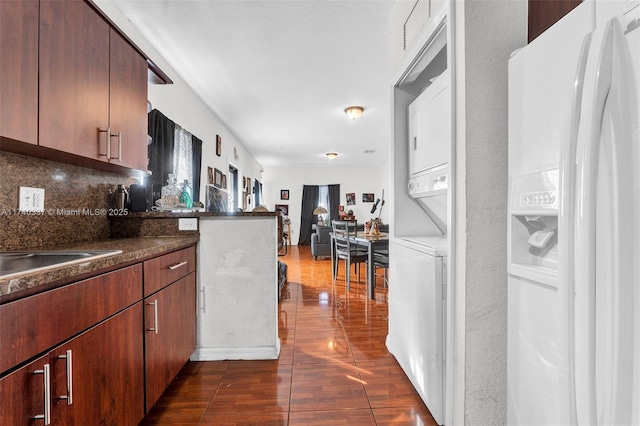 kitchen with stacked washer / dryer, dark hardwood / wood-style flooring, and decorative backsplash