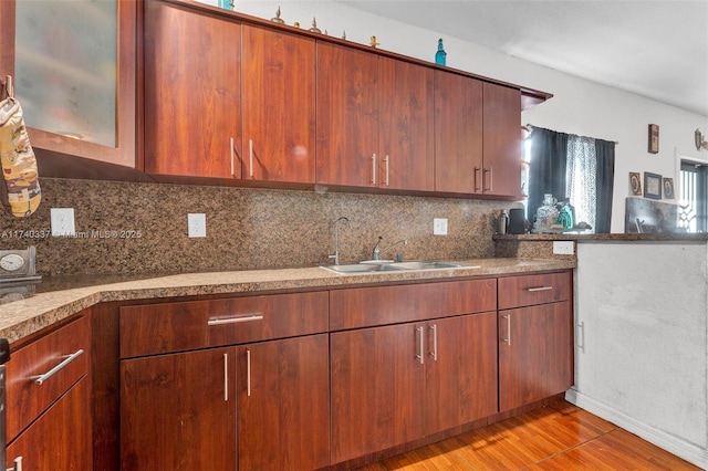 kitchen with tasteful backsplash, sink, and light hardwood / wood-style floors