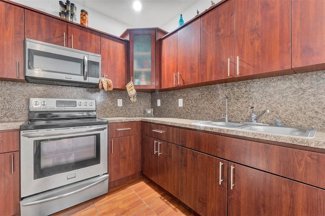 kitchen featuring sink, backsplash, light tile patterned flooring, and appliances with stainless steel finishes