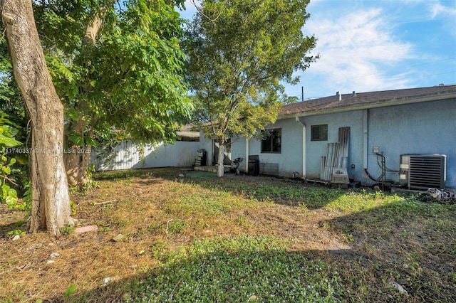 rear view of house featuring a lawn and central air condition unit