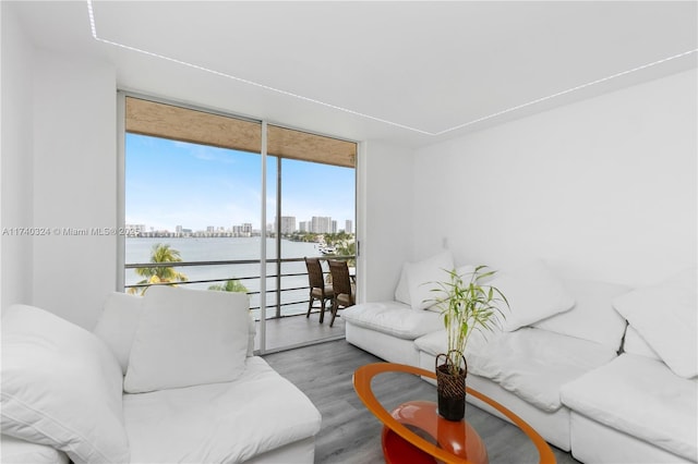 living room featuring hardwood / wood-style flooring, a water view, and a wall of windows