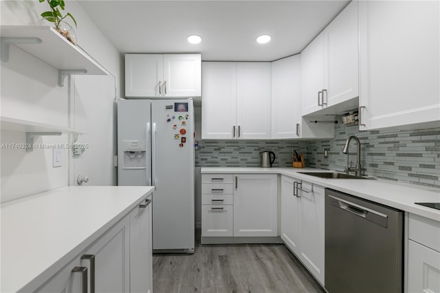 kitchen with tasteful backsplash, sink, white cabinets, white fridge with ice dispenser, and stainless steel dishwasher