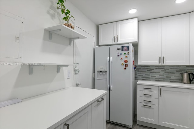 kitchen featuring white cabinetry, decorative backsplash, and white refrigerator with ice dispenser